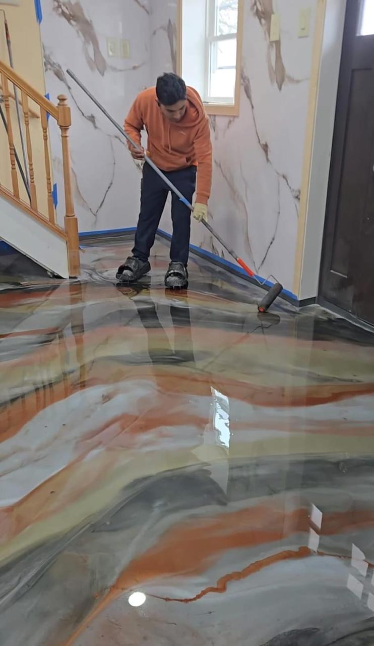 Professional installer applying a custom metallic epoxy floor inside a home